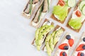 Set of organic season sandwiches on dry brown grain crispbreads with fresh vegetables, ripe fruits, fish preserves, cream cheese.