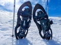 set of a pair of snowshoes or rackets of snow and two ski poles on the cold white snow ready to walk on the snowy mountain in a