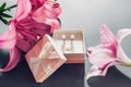 Set of pearl jewellery in pink gift box with flowers. Earrings and ring with lily on grey background Royalty Free Stock Photo