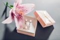 Set of pearl jewellery in pink gift box with flowers. Earrings and ring with lily on grey background Royalty Free Stock Photo