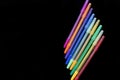 Set of pens of different colors on black background.