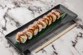 Set of philadelphia rolls with eel, smoked salmon, avocado and green bamboo leaf in a black ceramic plate with chopstick on a Royalty Free Stock Photo