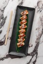 Set of philadelphia rolls with eel, smoked salmon, avocado and green bamboo leaf in a black ceramic plate with chopstick on a Royalty Free Stock Photo