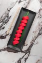 Set of philadelphia rolls with red flying fish caviar, avocado, salmon and green bamboo leaf in a black ceramic plate with Royalty Free Stock Photo