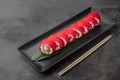 Set of philadelphia rolls with red flying fish caviar, avocado, salmon and green bamboo leaf in a black ceramic plate with Royalty Free Stock Photo