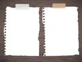 Set of pieces ripped white notebook paper are sticked on dark wooden wall or desk