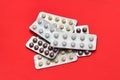 Set of pills blisters isolated on solid red background. Medical concept. Potent drugs. White, brown and yellow pills.