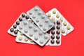 Set of pills blisters isolated on solid red background. Medical concept. Potent drugs. White, brown and yellow pills.