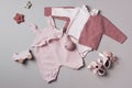 Set of pink clothes and accessories fot newborn girl. Toys, bodysuit, romper, knitted cardigan, shoes, bib on grey Royalty Free Stock Photo