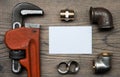 Set of pipes plumbing tools fittings and business card on the wooden background Royalty Free Stock Photo