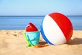 Set of plastic beach toys and colorful ball on sand near sea Royalty Free Stock Photo