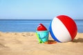Set of plastic beach toys and colorful ball on sand near sea Royalty Free Stock Photo
