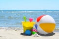 Set of plastic beach toys and inflatable ball on sand near sea. Space for text Royalty Free Stock Photo