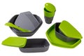 A set of plastic dishes for camping or for travel, green, food containers, plates and spoons, a plastic glass, on a white