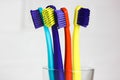 Set of plastic multicolored bright toothbrushes in a glass on a white background Royalty Free Stock Photo