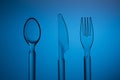 Set of plastic transparent spoon, knife and fork on a blue background Royalty Free Stock Photo