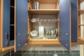 Set of plates, cups, knives, forks and wine glasses on the shelf in the kitchen cabinet Royalty Free Stock Photo