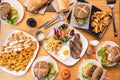 Set of popular Spanish dishes and hamburgers on wooden table. Loin and cheese sandwich, steak and egg, patatas bravas, fresh Royalty Free Stock Photo