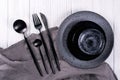 Set of porcelain handcraft grey and black plates and bowls cutlery set, linen napkin on a white wooden table. Royalty Free Stock Photo