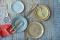 Set of porcelain plates of different types and colors on a blue planked table with crystal glasses and cutlery on the plates Royalty Free Stock Photo