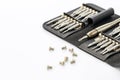 A set of precision screwdrivers in a black leather case on a white surface, with several screws scattered around Royalty Free Stock Photo