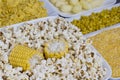 A set of products made from corn: popcorn, boiled grains, cereal, and corn grits. White plates