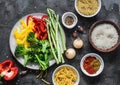 Set of products for vegetarian lunches - pasta, rice, bulgur and fresh vegetables on a dark background, top view