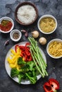 Set of products for vegetarian lunches - pasta, rice, bulgur and fresh vegetables on a dark background, top view