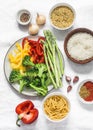 Set of products for vegetarian lunches - pasta, rice, bulgur and fresh vegetables on a light background, top view