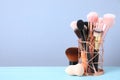 Set of professional makeup brushes in holder on blue wooden table. Space for text Royalty Free Stock Photo