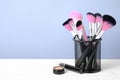 Set of professional makeup brushes in holder on white wooden table. Space for text Royalty Free Stock Photo
