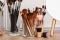 Set of professional makeup brushes and mirror on wooden table near white wall Royalty Free Stock Photo