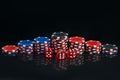 A set of pyramids of poker chips and red dice, on a black background with reflection Royalty Free Stock Photo