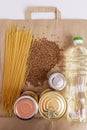 A set of quarantined products laid out on an eco-friendly paper bag. Spaghetti, cereals, cans with canned bottle with vegetable