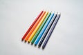 Set of rainbow colored pencils, diagonally positioned on white piece of blank paper Royalty Free Stock Photo