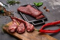 Set of Raw uncooked black angus beef tomahawk steaks on bones and veal tenderloin served with chilli and peppercorns. Rustic style