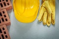 Set of red bricks hard hat safety gloves on concrete background Royalty Free Stock Photo