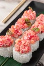 Set of rolls with salmon, red flying fish caviar and green bamboo leaf in a black ceramic plate with chopstick on a bright Royalty Free Stock Photo