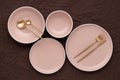A set of round beige plates of different sizes on the table, top view. Golden cutlery and serving utensils. Modern trendy ceramic