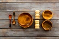 Set of rustic wooden tableware - bowls and utensils on dark wooden background top view pattern