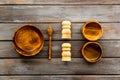 Set of rustic wooden tableware - bowls and utensils on dark wooden background top view pattern