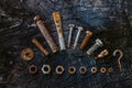 Set of rusty screws, nuts and small tools on a dark wooden background. Royalty Free Stock Photo