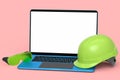 Set of safety helmets or hard caps, goggles and laptop on pink background