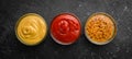 Set of sauces in bowls. Mustard and ketchup sauce in a bowl on a black stone background.