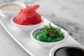 Set of sauces for sushi on a white plate, ginger, soy, sesame, seaweed. bright textured marble background, side view, close-up Royalty Free Stock Photo