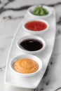 Set of sauces for sushi on a white plate, wasabi, spicy, cheesy, soy. bright textured marble background, side view, close-up Royalty Free Stock Photo