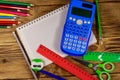 Set of school stationery supplies. Blank notepad, calculator, rulers, pencils, pens, scissors and sharpener on wooden desk Royalty Free Stock Photo