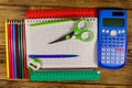 Set of school stationery supplies. Blank notepad, calculator, rulers, pencils, pens, scissors and sharpener on wooden desk Royalty Free Stock Photo