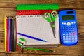 Set of school stationery supplies. Blank notepad, calculator, rulers, pencils, pens, scissors and sharpener on wooden desk Royalty Free Stock Photo