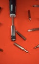 A set of a screwdriver with replaceable bits and bits for her for working with small parts on a red background Royalty Free Stock Photo